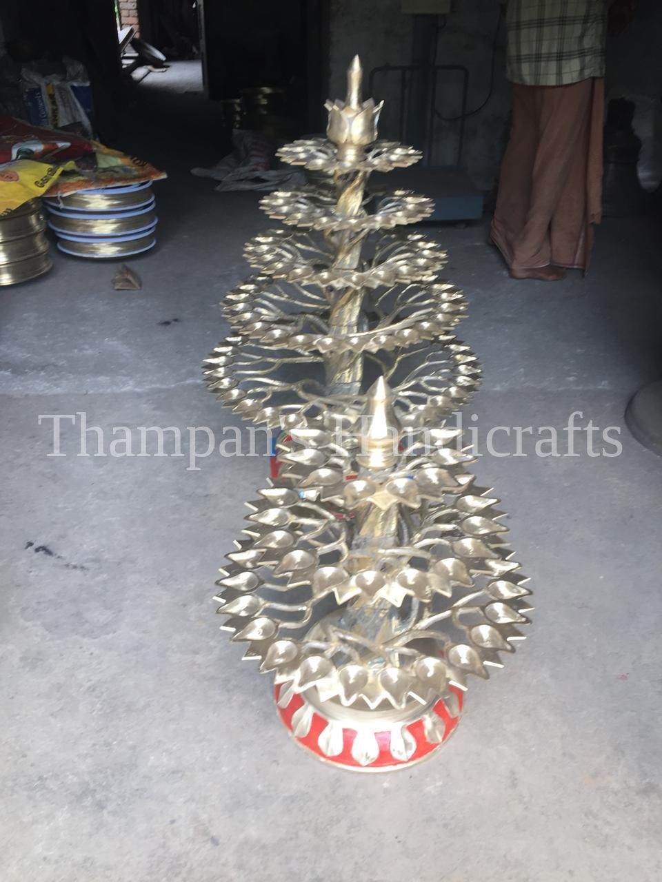 A tall tiered brass alu vilakku lamp made in Mannar, Kerala